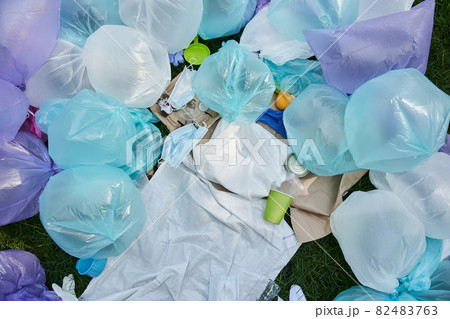 Cluttered and messy ground with piece of plastic bags, used protective masks and bottles 82483763