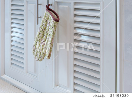 The heat-resistant gloves in the leaf pattern is hanging on the handle of the cabinet. 82493080