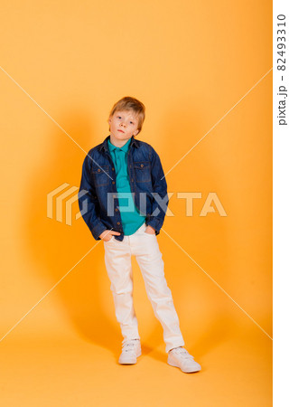 Grimacing emotional redhead fasion boy posing in yellow studio Grimacing emotional redhead fasion boy posing in yellow studio 82493310