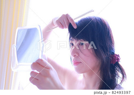 鏡を見て髪をいじる女性 82493397