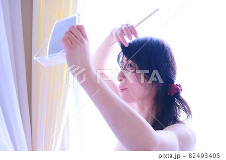 鏡を見て髪をいじる女性 82493405