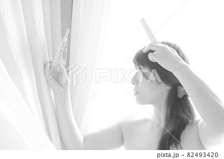 鏡を見て髪をいじる女性 82493420