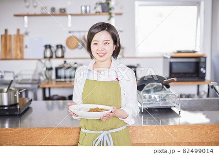 キッチンでカレーライスを持って立つエプロン姿の若い女性 キッチンでカレーライスを持って立つエプロン姿の若い女性 82499014