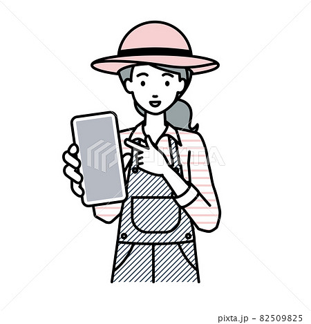 立ってスマートフォンを指差してこちらに向けて見せている農家の女性 82509825
