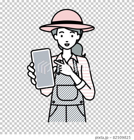 立ってスマートフォンを指差してこちらに向けて見せている農家の女性 82509825