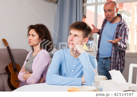 Upset teenage boy scolded by mother and father Upset teenage boy scolded by mother and father 82514597