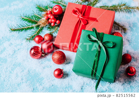 Festive boxes on a blue background with Christmas toys balls a branch of fluffy spruce sparkles confetti. New Year Christmas concept. Flat festive mockup with copy space Festive boxes on a blue background with Christmas toys balls a branch of fluffy spruce sparkles confetti. New Year Christmas concept. Flat festive mockup with copy space 82515562