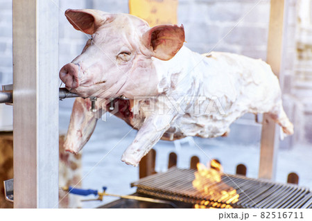 Close-up of a whole roasted pig turning on the spit 82516711