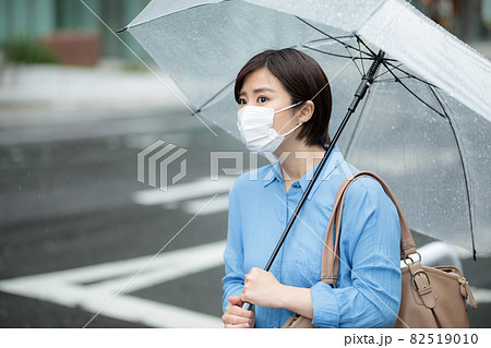 若い女性　雨　傘　マスク 82519010
