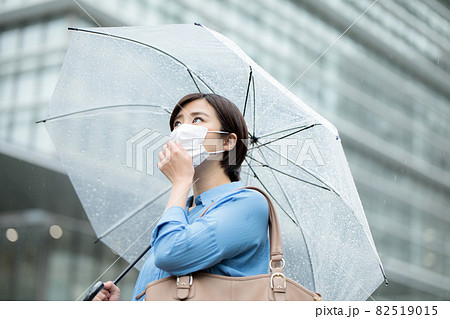 若い女性　雨　傘　マスク 82519015
