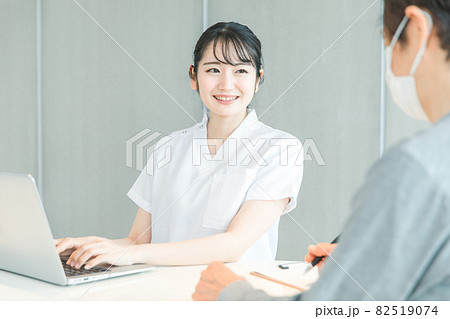 パソコンで受付する白衣の女性と患者（笑顔） 82519074