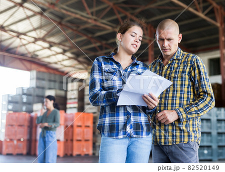 Female manager discussing order list with male worker at warehouse 82520149