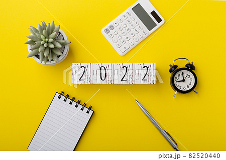 2022 wood block with calculator and notebook on yellow background 82520440