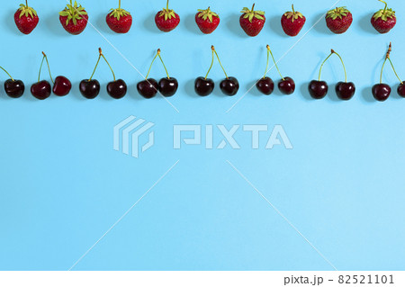 Fresh cherries and strawberries on blue background, top view 82521101