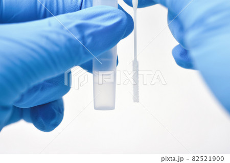 Medical personnel compare a cotton swab and saline extraction tube for diagnostic covid-19 82521900