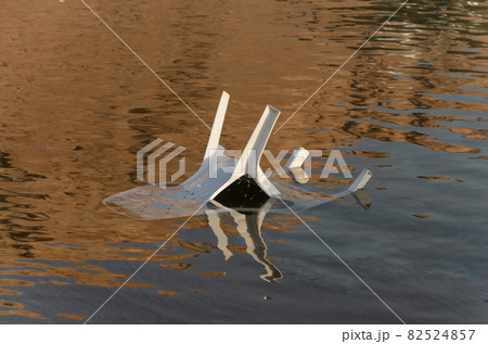 plastic white chairs in the water near the shore on the beach 82524857