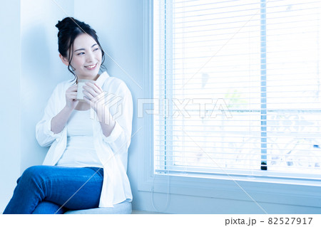 日差しがさしこむリビングでコーヒーを飲みながら寛ぐ女性 日差しがさしこむリビングでコーヒーを飲みながら寛ぐ女性 82527917
