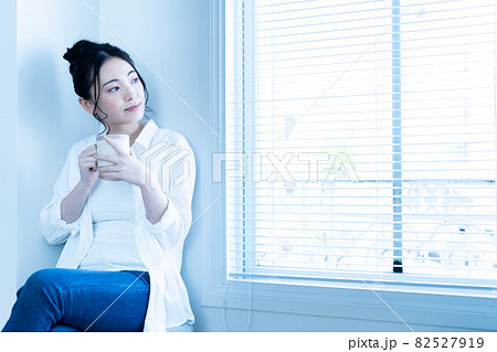 日差しがさしこむリビングでコーヒーを飲みながら寛ぐ女性 日差しがさしこむリビングでコーヒーを飲みながら寛ぐ女性 82527919