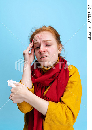 Cropped vertical portrait of young Caucasian girl feeling sick, having a cold isolated over blue background Cropped vertical portrait of young Caucasian girl feeling sick, having a cold isolated over blue background 82533422