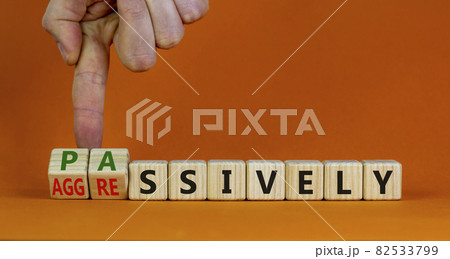 Passively or aggressively symbol. Businessman turns cubes and changes the word passively to aggressively. Psychological and passively or aggressively concept. Beautiful orange background, copy space. 82533799