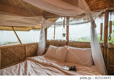 Inside the bedroom that made of wooden thatched with mosquito net, book, retro camera among the mountain Inside the bedroom that made of wooden thatched with mosquito net, book, retro camera among the mountain 82533845