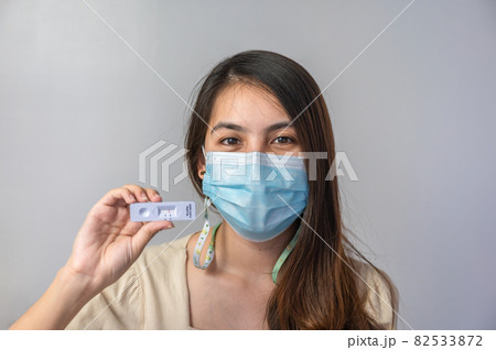 Asian woman wearing face mask showing negative result of rapid antigen test kit of home use 82533872