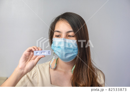 Asian woman wearing face mask showing negative result of rapid antigen test kit of home use Asian woman wearing face mask showing negative result of rapid antigen test kit of home use 82533873