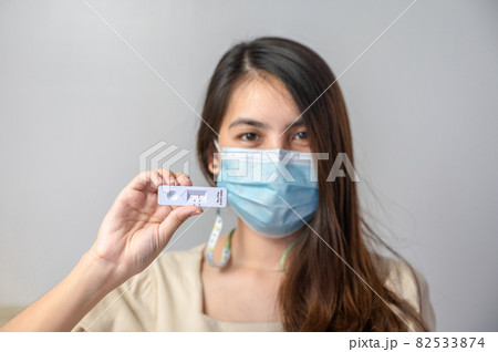 Asian woman wearing face mask showing negative result of rapid antigen test kit of home use 82533874