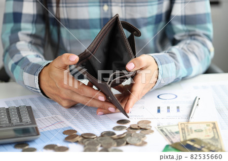 Woman shows empty wallet on table coins and documents Woman shows empty wallet on table coins and documents 82535660