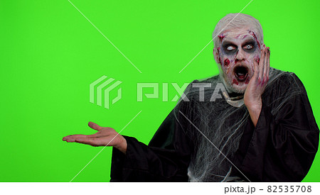 Scary wounded Halloween zombie undead man showing thumbs up and pointing at left on blank space Scary wounded Halloween zombie undead man showing thumbs up and pointing at left on blank space 82535708