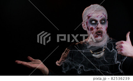 Halloween zombie showing thumbs up, pointing empty place advertising area for commercial text logo 82536239