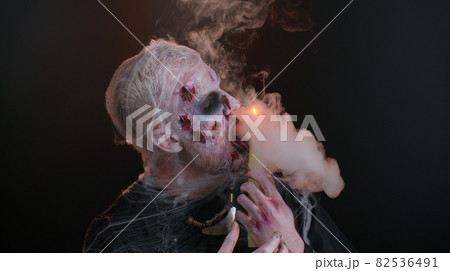 Frightening man with Halloween zombie bloody makeup spells conjures over candle, voodoo rituals 82536491