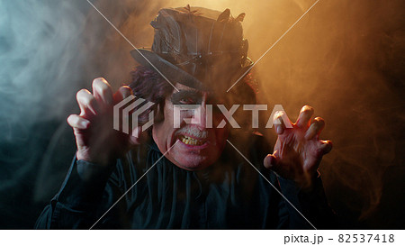 Sinister man with horrible scary Halloween witcher makeup in costume making faces trying to scare Sinister man with horrible scary Halloween witcher makeup in costume making faces trying to scare 82537418