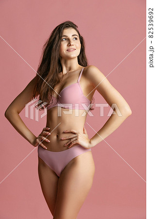 Portrait of young beautiful slim woman in lingerie posing isolated over pink studio background. Natural beauty concept. Portrait of young beautiful slim woman in lingerie posing isolated over pink studio background. Natural beauty concept. 82539692