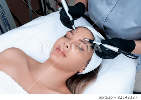 Cosmetology. Beautiful Woman At Spa Clinic Receiving Stimulating Electric Facial Treatment From Therapist. Closeup Of Young Female Face During Microcurrent Therapy Cosmetology. Beautiful Woman At Spa Clinic Receiving Stimulating Electric Facial Treatment From Therapist. Closeup Of Young Female Face During Microcurrent Therapy 82543337