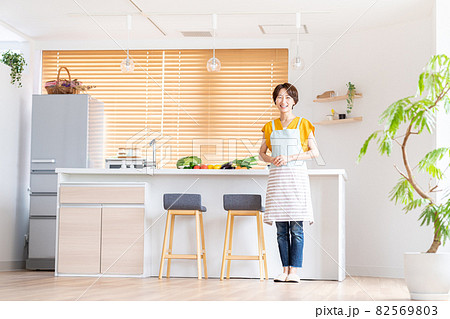 キッチンに立つ笑顔のミドル女性 82569803