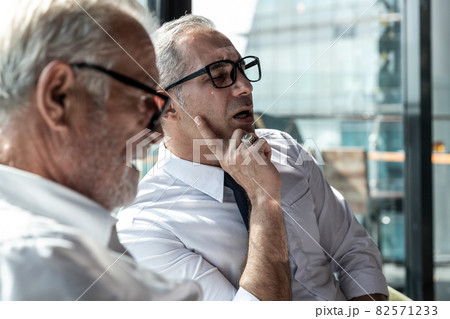 Picture of yoPicture of young business man taking to his older business partnerung business man taking to his older business partner. They are in white shirt and black tie. They are in a hotel lobby. Picture of yoPicture of young business man taking to his older business partnerung business man taking to his older business partner. They are in white shirt and black tie. They are in a hotel lobby. 82571233