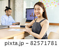 Portrait of a happy casual asian businesswoman  sitting at her workplace in office.She doing some paperwork at the office.Businesspeople smiling coworking commenting and showing growth graphic and 82571781