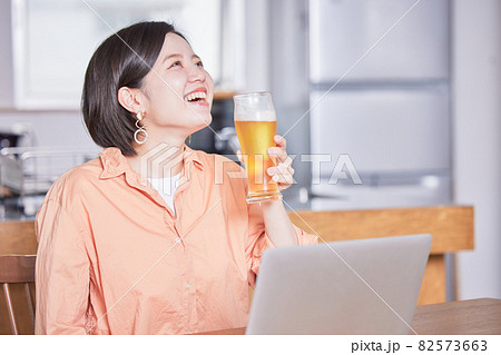 オンライン飲み会でビールを飲む若い女性 82573663