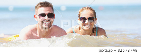 Young happy beautiful couple woman and man lying in sea water 82573748