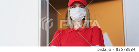 Portrait of woman courier in protective medical mask in uniform Portrait of woman courier in protective medical mask in uniform 82573934