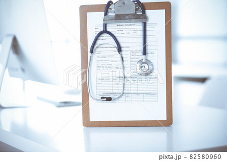 Stethoscope and clipboard with medication history records are on the table at the doctor's working place. Medicine and health care concept 82580960