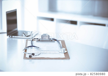 Stethoscope and clipboard with medication history records are on the table at the doctor's working place. Medicine and health care concept 82580980