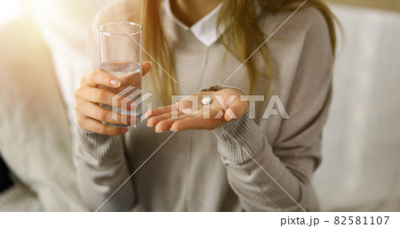 Close-up woman holding pills time to take medications, cure for headache. Medicine concept during self isolation and Coronavirus pandemic Close-up woman holding pills time to take medications, cure for headache. Medicine concept during self isolation and Coronavirus pandemic 82581107