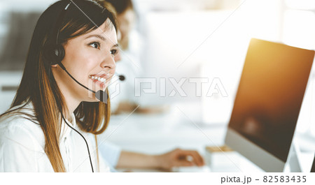 Asian woman working at customer service office. Business concept. Group of diverse operators at work in sunny call center. Asian woman working at customer service office. Business concept. Group of diverse operators at work in sunny call center. 82583435