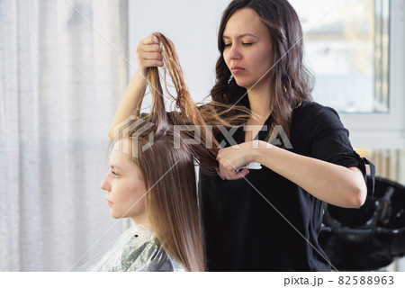 Close up of hairdressers hands drying long blond hair with blow dryer and round brush 82588963