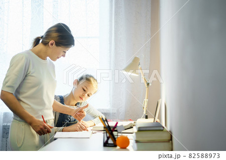 Mother and daughter doing homework together, styding and learning concept, doing tasks for school Mother and daughter doing homework together, styding and learning concept, doing tasks for school 82588973