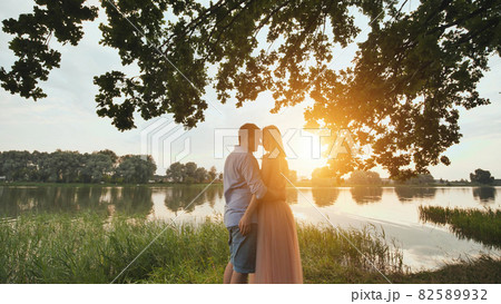 A young couple stands on a lake at sunset. Video on the move. A young couple stands on a lake at sunset. Video on the move. 82589932
