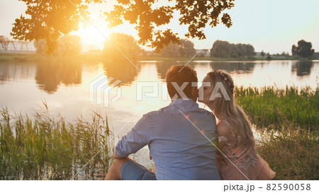 A young couple sits on a lake at sunset. A young couple sits on a lake at sunset. 82590058