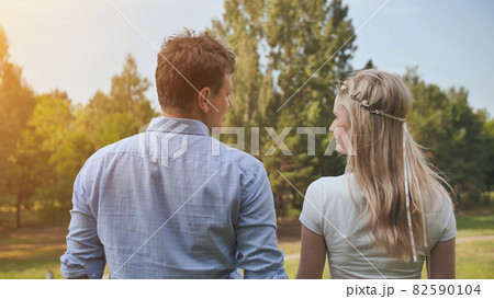 Young man and woman stand with their backs in the park Young man and woman stand with their backs in the park 82590104